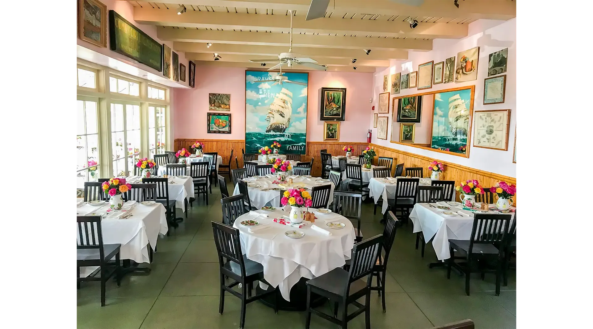 Ivy at the Shore’s dining room set with white linens and pitchers of roses — ready for a rehearsal-dinner party